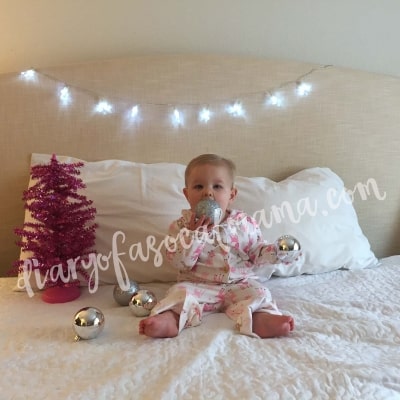 Baby Christmas photo on bed with bulb